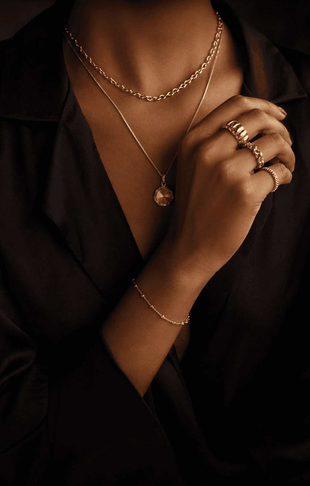 Artisan gold jewelry worn against dark linen